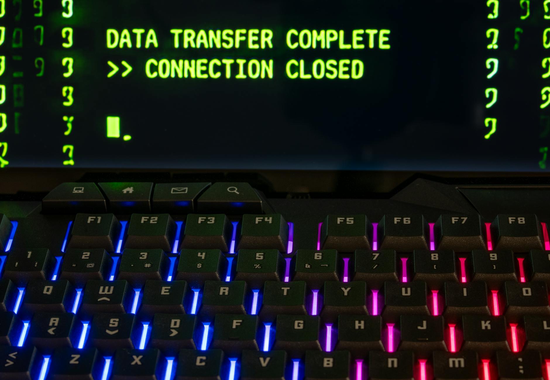 Close-up of a RGB lit keyboard with a screen displaying 'Data Transfer Complete'.