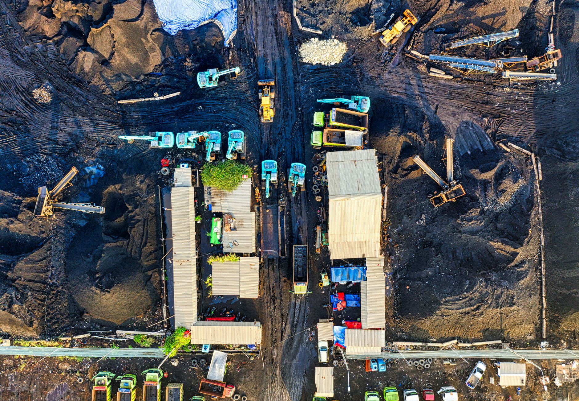 High-angle aerial view of a bustling construction site in North Jakarta, Indonesia with machinery and trucks.